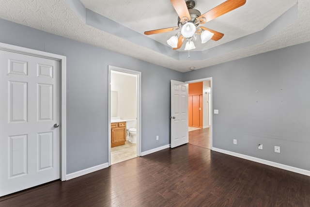 1090 Sugarberry Ln, Springfield, TN 37172 - unfurnished bedroom featuring baseboards, wood finished floors, a tray ceiling, ensuite bath, and ceiling fan