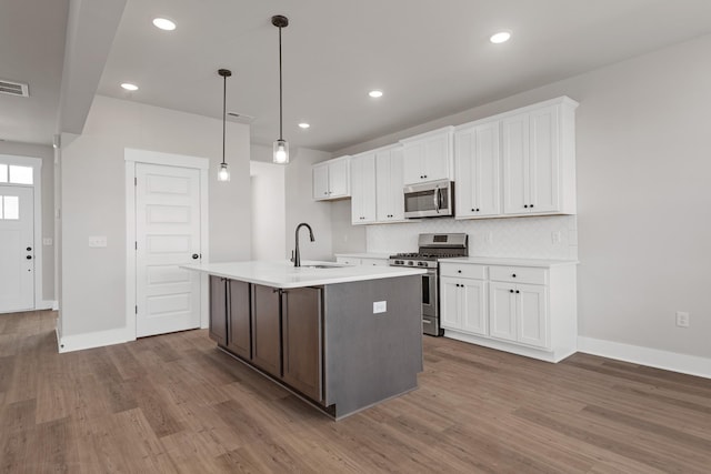 2416 Burton Dr, White House, TN 37188 - kitchen with stainless steel appliances, a sink, wood finished floors, white cabinetry, and recessed lighting