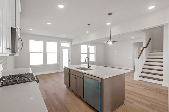 2416 Burton Dr, White House, TN 37188 - kitchen featuring appliances with stainless steel finishes, a sink, light wood-style floors, ceiling fan, and white cabinetry