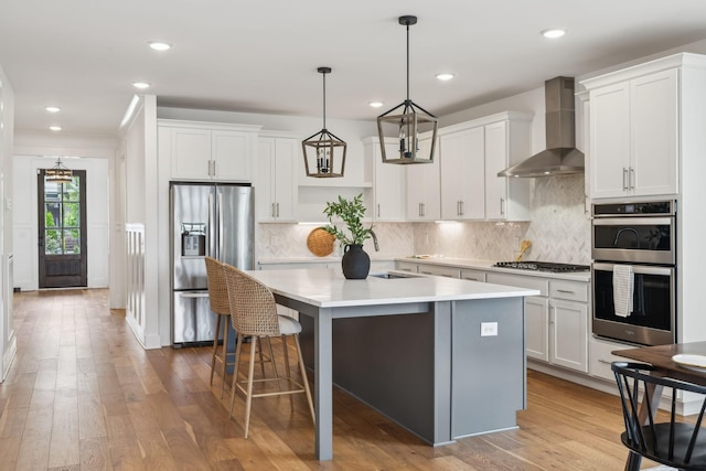 3298 Vinemont Dr, Thompsons Station, TN 37179 - kitchen featuring appliances with stainless steel finishes, wall chimney range hood, a sink, a kitchen island with sink, and light countertops
