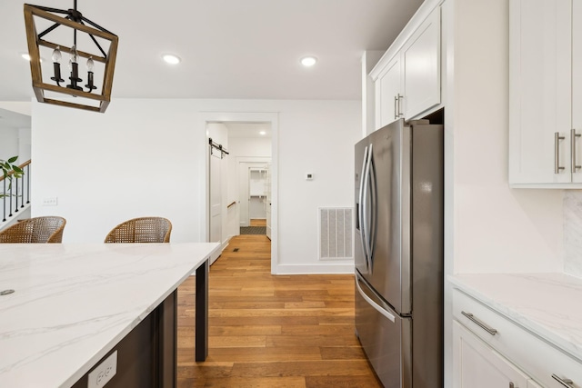 3298 Vinemont Dr, Thompsons Station, TN 37179 - kitchen with stainless steel fridge with ice dispenser, light wood-style floors, white cabinets, recessed lighting, and light stone countertops