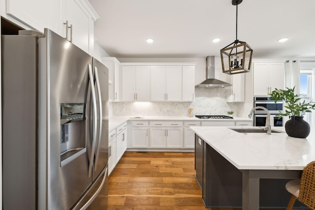 3298 Vinemont Dr, Thompsons Station, TN 37179 - kitchen featuring appliances with stainless steel finishes, wall chimney exhaust hood, a sink, light wood-style floors, and white cabinets