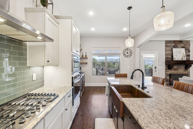 413 Eagle Rdg, Nashville, TN 37209 - kitchen with wall chimney range hood, a stone fireplace, stainless steel gas stovetop, decorative backsplash, and white cabinets