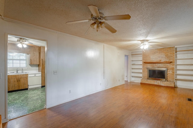 4510 Ravenwood Dr E, Chattanooga, TN 37415 - unfurnished living room featuring a textured ceiling, a ceiling fan, light wood-style floors, a brick fireplace, and built in shelves