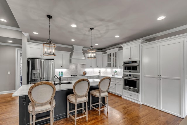 1132 Pretender Way, Columbia, TN 38401 - kitchen with appliances with stainless steel finishes, wall chimney range hood, ornamental molding, a kitchen island with sink, and light countertops