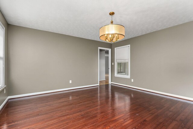 829 Navajo Trl, Mcminnville, TN 37110 - empty room featuring wood finished floors, a chandelier, baseboards, and healthy amount of natural light