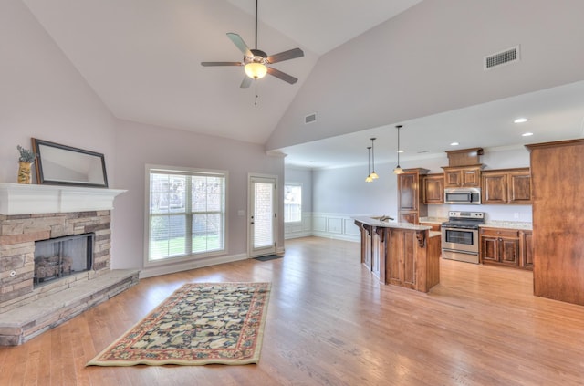 5502 Reflection Rd, Smyrna, TN 37167 - kitchen featuring appliances with stainless steel finishes, open floor plan, brown cabinets, a kitchen bar, and a ceiling fan