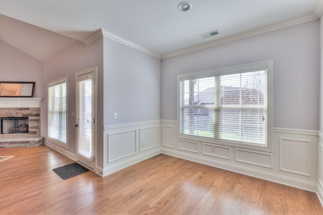 5502 Reflection Rd, Smyrna, TN 37167 - empty room featuring a stone fireplace, light wood-style flooring, wainscoting, and ornamental molding