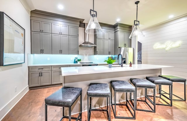1108 Greenwood Ave, Nashville, TN 37206 - kitchen featuring wall chimney exhaust hood, stainless steel fridge, gray cabinetry, a breakfast bar area, and wood walls