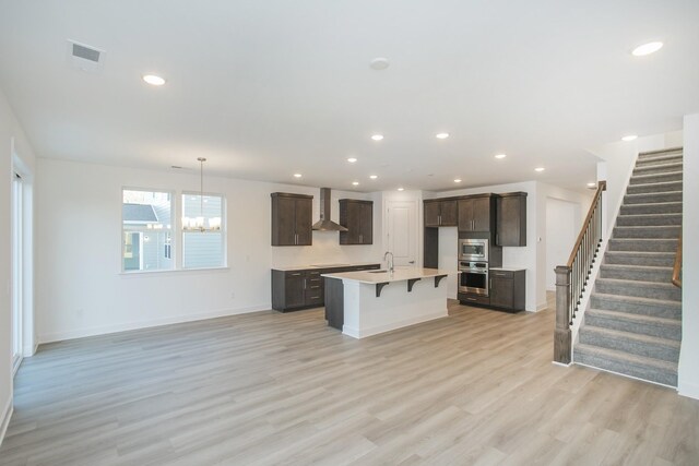 106 W Cassa Way, Mount Juliet, TN 37122 - kitchen with appliances with stainless steel finishes, dark brown cabinetry, a sink, light wood-style flooring, and an island with sink