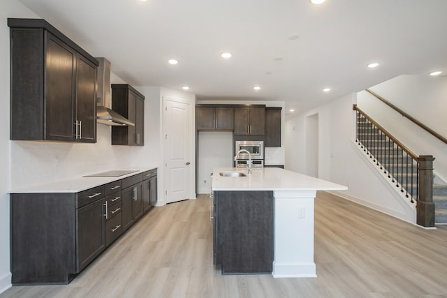 106 W Cassa Way, Mount Juliet, TN 37122 - kitchen with wall chimney range hood, light wood finished floors, stainless steel microwave, a center island with sink, and black electric cooktop