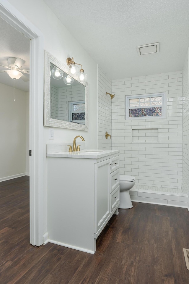 1313 W 46th St, Chattanooga, TN 37409 - bathroom with toilet, wood finished floors, tiled shower, vanity, and a ceiling fan