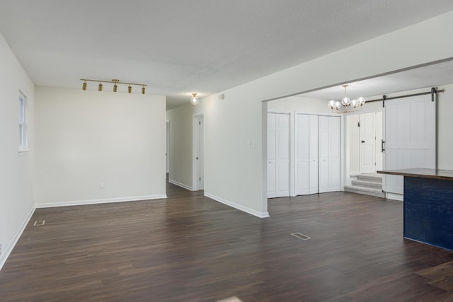 1313 W 46th St, Chattanooga, TN 37409 - unfurnished living room featuring a barn door, a chandelier, dark wood finished floors, and baseboards