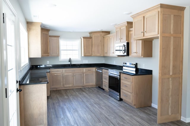 130 Mazie Dr, Lafayette, TN 37083 - kitchen with stainless steel appliances, light brown cabinetry, a sink, dark countertops, and light wood-style floors