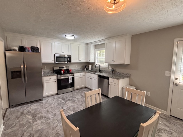 1040 Rebecca Dr, Burns, TN 37029 - kitchen featuring appliances with stainless steel finishes, white cabinets, a textured ceiling, stone counters, and a sink