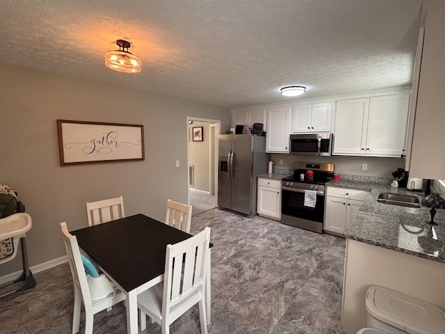 1040 Rebecca Dr, Burns, TN 37029 - kitchen with appliances with stainless steel finishes, white cabinetry, dark stone counters, a sink, and a textured ceiling