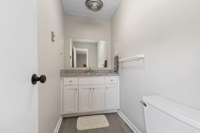 1040 Rebecca Dr, Burns, TN 37029 - bathroom with wood finished floors, toilet, baseboards, vanity, and a textured ceiling