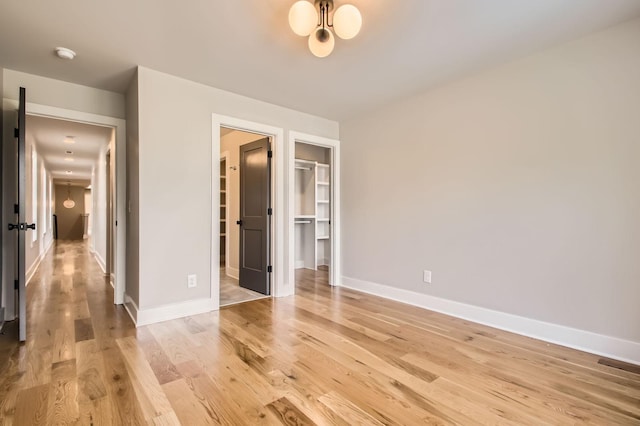 549B Stevenson St, Nashville, TN 37209 - unfurnished bedroom featuring light wood-style floors, a spacious closet, baseboards, a closet, and a chandelier