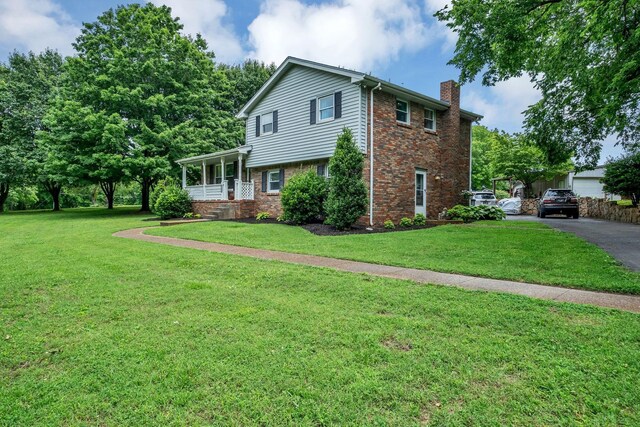 2729 Heights Circle Rd, Greenbrier, TN 37073 - view of front of home with a chimney, brick siding, a front lawn, and covered porch