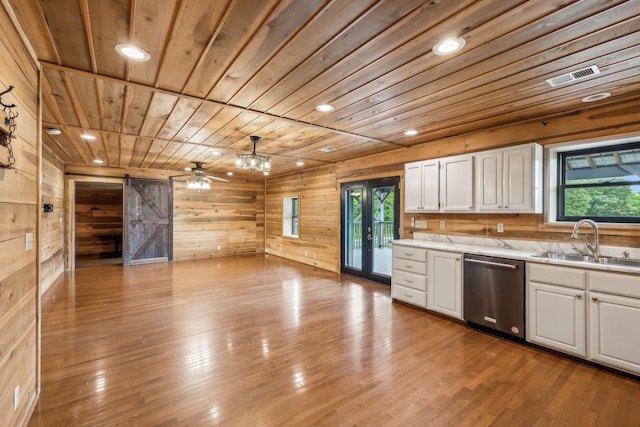 210 S 3rd St, Dickson, TN 37055 - kitchen with stainless steel dishwasher, a barn door, a sink, wood walls, and white cabinetry