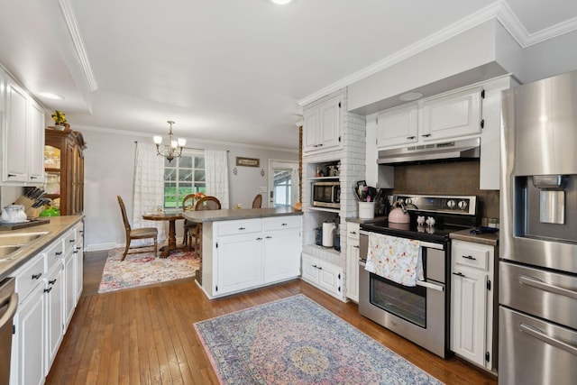 1106 5th Ave, Lawrenceburg, TN 38464 - kitchen with appliances with stainless steel finishes, under cabinet range hood, a peninsula, a chandelier, and dark wood-type flooring