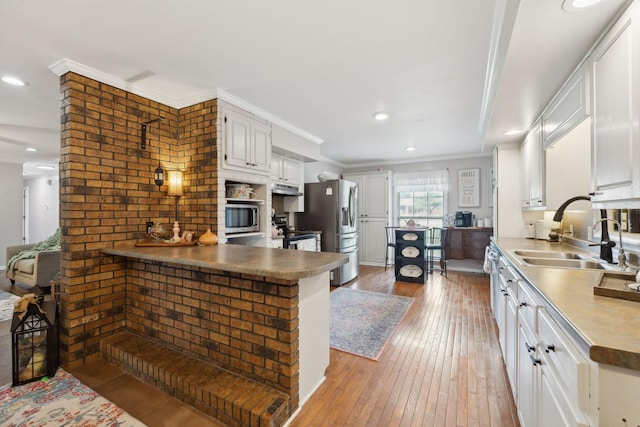 1106 5th Ave, Lawrenceburg, TN 38464 - kitchen featuring a sink, appliances with stainless steel finishes, light wood-style floors, white cabinetry, and a peninsula