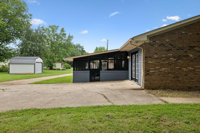1106 5th Ave, Lawrenceburg, TN 38464 - view of property exterior featuring a yard, a sunroom, an outdoor structure, and brick siding