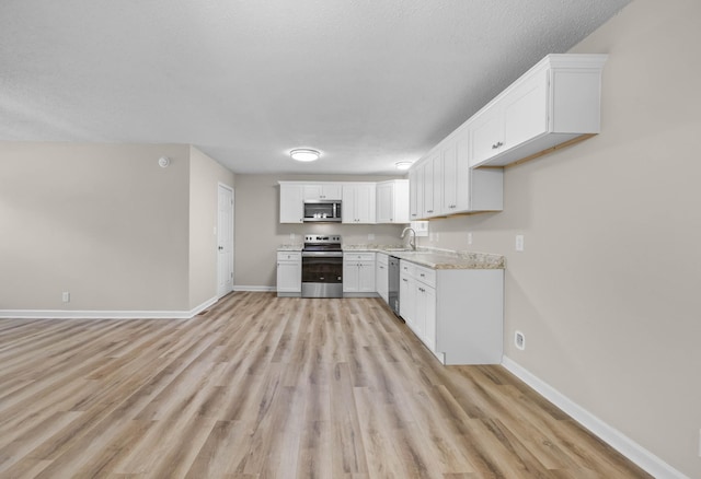 517 Overton Dr, Clarksville, TN 37042 - kitchen with stainless steel appliances, baseboards, light wood-style flooring, white cabinets, and a textured ceiling