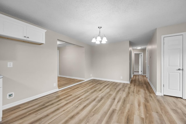 517 Overton Dr, Clarksville, TN 37042 - unfurnished dining area with light wood finished floors, a textured ceiling, a chandelier, and baseboards