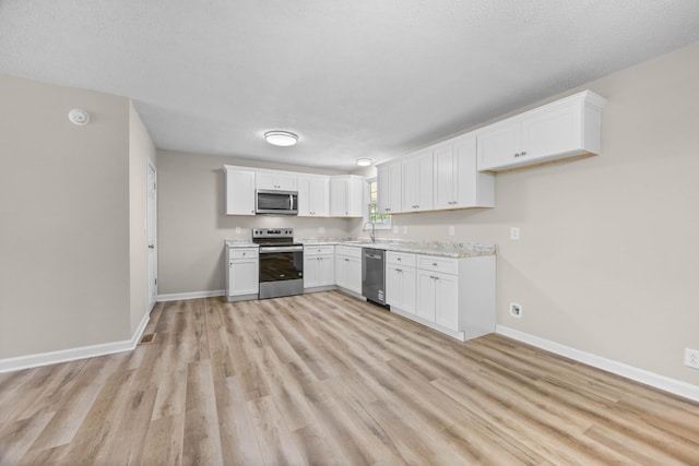 517 Overton Dr, Clarksville, TN 37042 - kitchen with appliances with stainless steel finishes, baseboards, light countertops, light wood-style floors, and white cabinetry