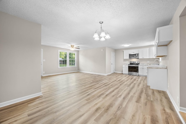 517 Overton Dr, Clarksville, TN 37042 - unfurnished living room with a chandelier, light wood finished floors, a ceiling fan, a textured ceiling, and baseboards