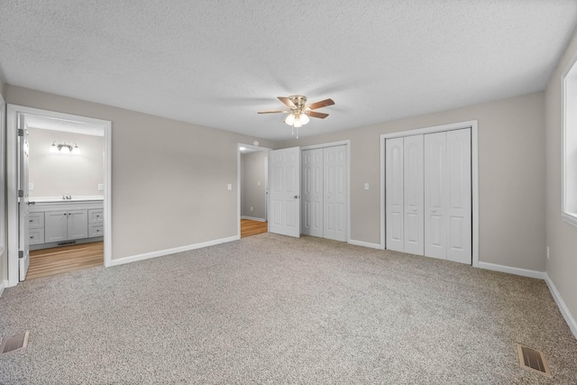 517 Overton Dr, Clarksville, TN 37042 - unfurnished bedroom featuring two closets, light colored carpet, baseboards, a textured ceiling, and a sink