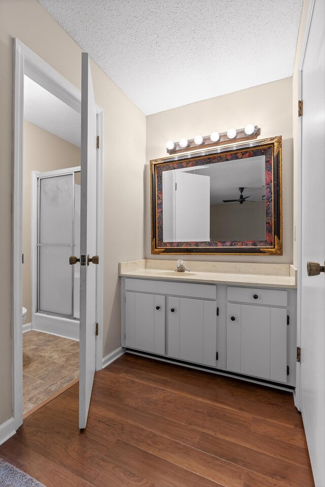 3554 Mountain Creek Rd, Chattanooga, TN 37415 - bathroom featuring vanity, wood finished floors, a stall shower, a textured ceiling, and baseboards
