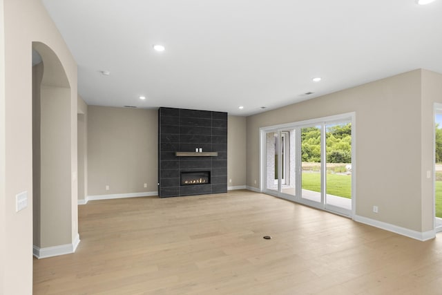 5971 Hunt Valley Dr, Spring Hill, TN 37174 - unfurnished living room with light wood-style flooring, recessed lighting, a tile fireplace, and arched walkways
