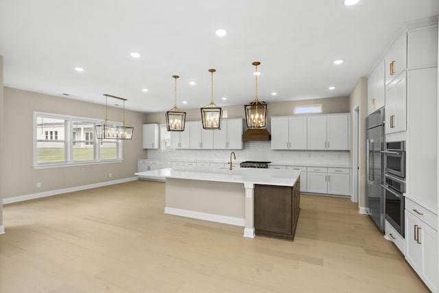 5971 Hunt Valley Dr, Spring Hill, TN 37174 - kitchen with appliances with stainless steel finishes, light countertops, decorative backsplash, premium range hood, and light wood-style flooring