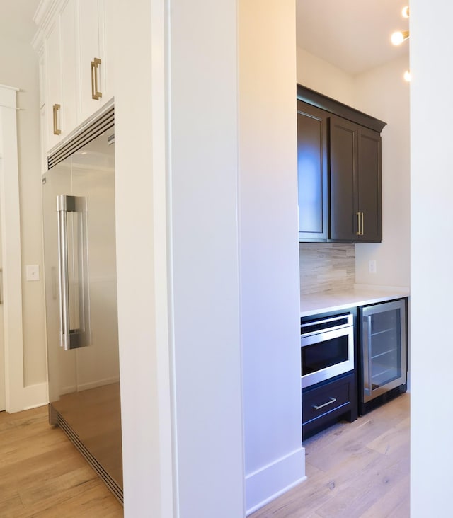 1266 Potter Ln, Gallatin, TN 37066 - kitchen with built in appliances, wine cooler, light wood-style floors, light countertops, and decorative backsplash