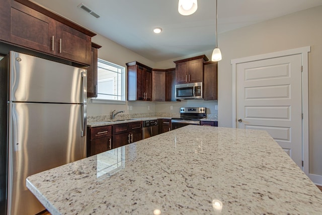 3010 Coriander Dr, Spring Hill, TN 37174 - kitchen featuring stainless steel appliances, a sink, dark brown cabinets, light stone countertops, and decorative light fixtures