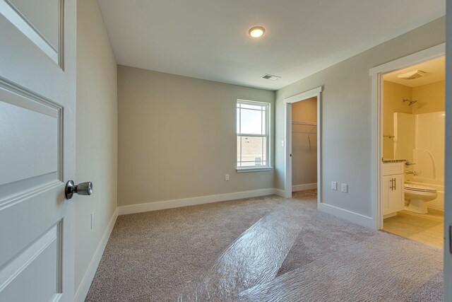 3010 Coriander Dr, Spring Hill, TN 37174 - unfurnished bedroom featuring light carpet, baseboards, a walk in closet, and ensuite bath