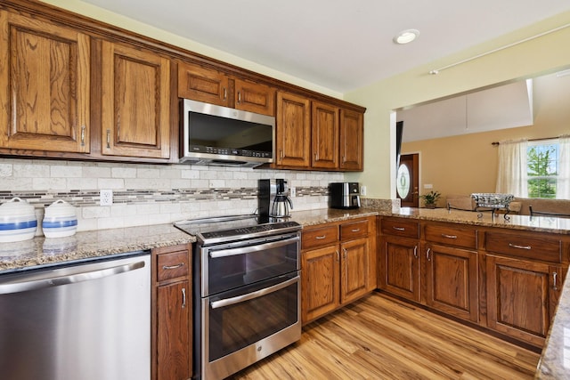2917 York Rd, Pleasant View, TN 37146 - kitchen featuring stainless steel appliances, light wood-type flooring, light stone countertops, and brown cabinetry