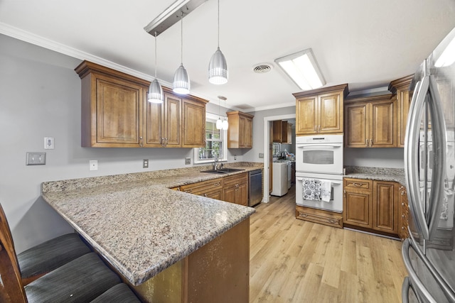 255 Whispering Hills Dr, Dover, TN 37058 - kitchen with appliances with stainless steel finishes, a sink, a peninsula, brown cabinetry, and ornamental molding