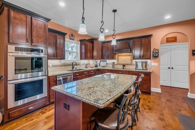 3112 Timberdale Dr, Clarksville, TN 37042 - kitchen with appliances with stainless steel finishes, a sink, custom exhaust hood, light stone counters, and light wood-style flooring