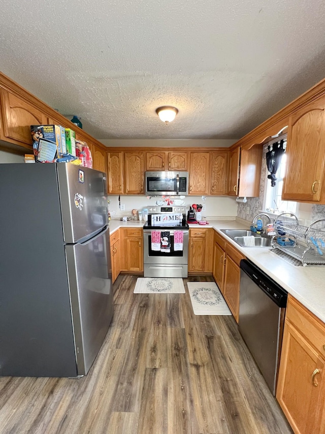 108 Josephines Ct, Oak Grove, KY 42262 - kitchen with stainless steel appliances, wood finished floors, a sink, a textured ceiling, and light countertops