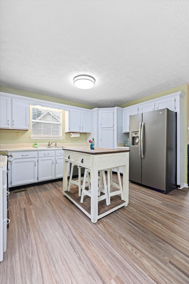 152 Scenic Cir, Ringgold, GA 30736 - kitchen with stainless steel fridge with ice dispenser, light countertops, wood finished floors, white cabinets, and a textured ceiling