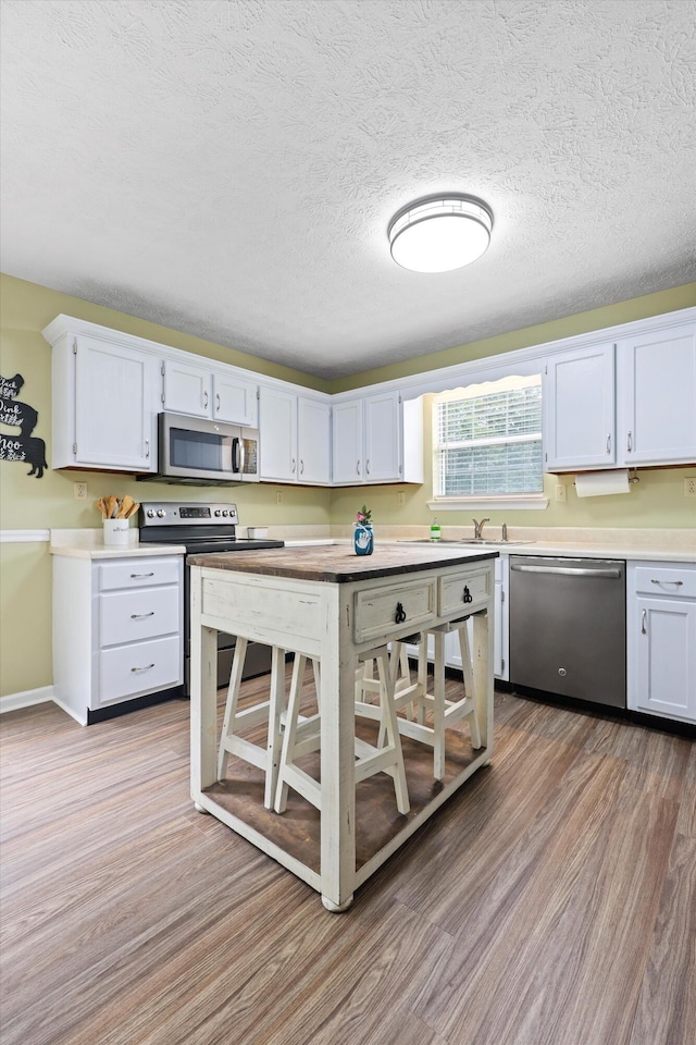 152 Scenic Cir, Ringgold, GA 30736 - kitchen featuring appliances with stainless steel finishes, light wood finished floors, white cabinets, light countertops, and a textured ceiling