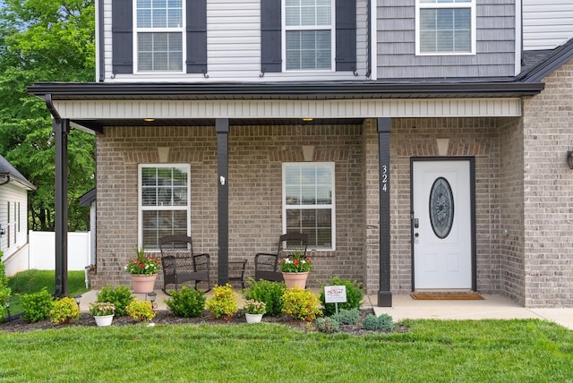 324 Kildeer Dr, Clarksville, TN 37040 - view of exterior entry with covered porch, brick siding, and a yard