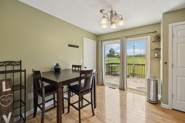 1809 Mosley Ferry Rd, Chapmansboro, TN 37035 - dining space featuring a chandelier, light wood-style flooring, a textured ceiling, and baseboards