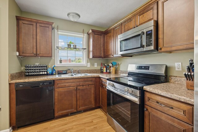 1809 Mosley Ferry Rd, Chapmansboro, TN 37035 - kitchen featuring stainless steel appliances, a sink, light wood-style flooring, light countertops, and brown cabinets