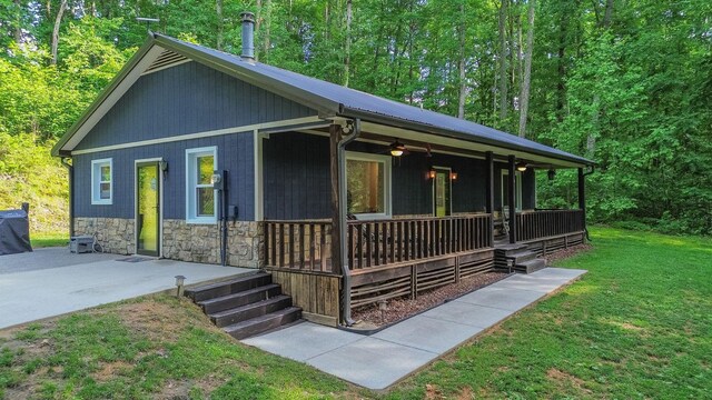 7872 Oscar Green Rd, Primm Springs, TN 38476 - view of front of home with covered porch, a front lawn, a ceiling fan, stone siding, and metal roof