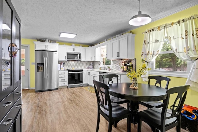 210 Lankford St, Bruceton, TN 38317 - kitchen featuring stainless steel appliances, tasteful backsplash, light wood-style flooring, light countertops, and white cabinetry