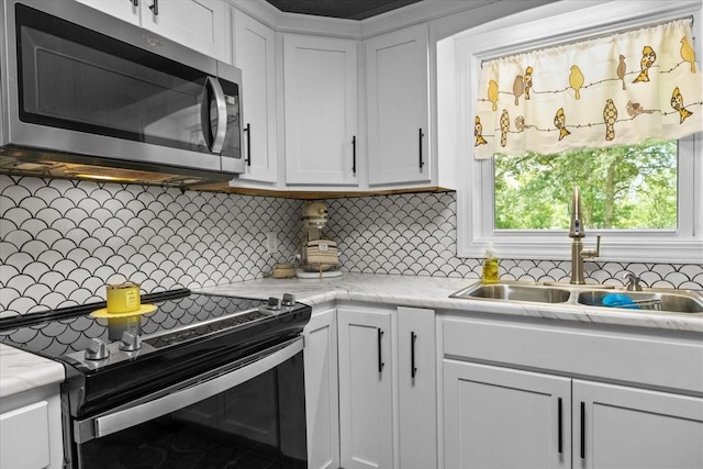 210 Lankford St, Bruceton, TN 38317 - kitchen with stainless steel microwave, electric range, a sink, white cabinetry, and decorative backsplash